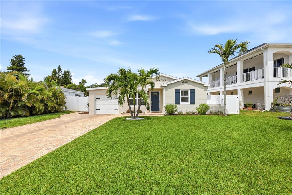 A single-story house with a white garage, blue front door, and a large front lawn — 105 3RD STREET, BELLEAIR BEACH, FL