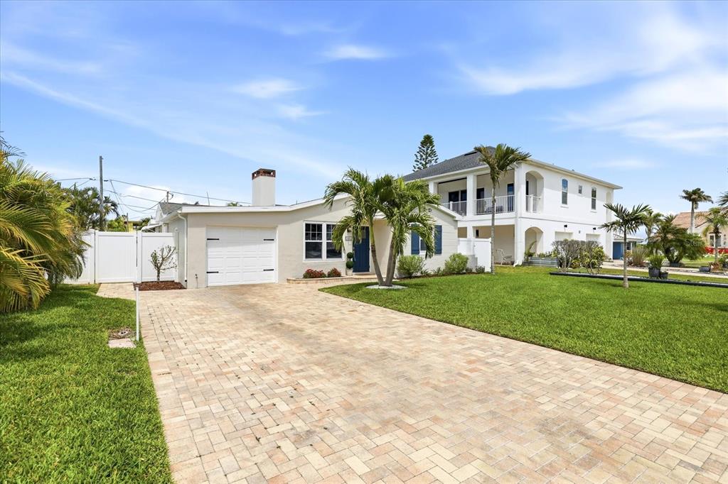 A single-story house with a white garage and a paved driveway sits on a lawn — 105 3RD STREET, BELLEAIR BEACH, FL