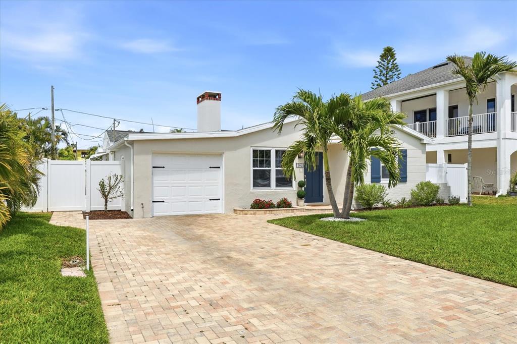 A single-story house with a paved driveway, white garage door, and a palm tree — 105 3RD STREET, BELLEAIR BEACH, FL