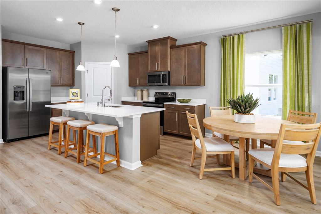 A kitchen features brown cabinets, a white island with bar stools, and a dining area — 1016 OCEAN LODGE ROAD, LADY LAKE, FL