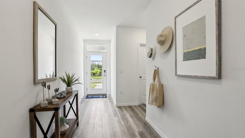 A bright entryway features light wood-look flooring, a console table, and a glass-paneled front door — 11952 NOBLE CHASE PATH, DADE CITY, FL