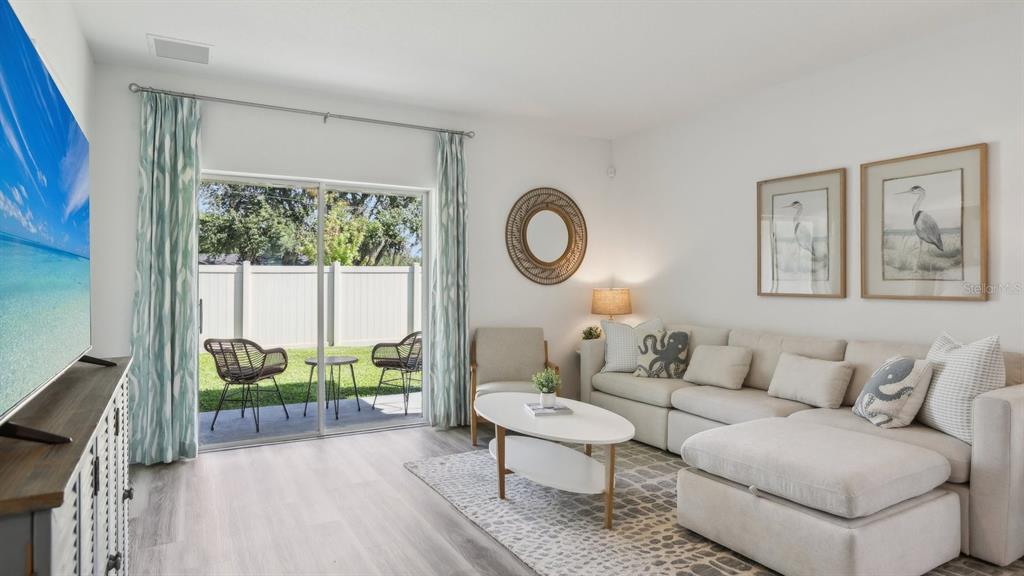 A living room features a sectional sofa, a coffee table, and sliding doors to a patio — 11952 NOBLE CHASE PATH, DADE CITY, FL