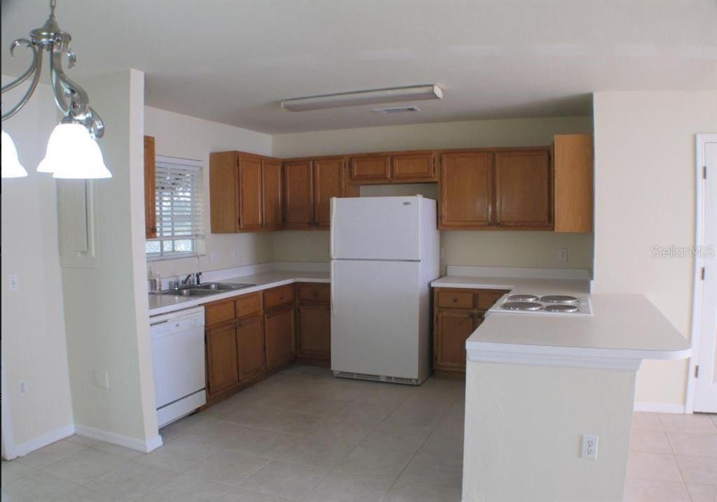 A kitchen with oak cabinets, white appliances, a peninsula, and tile flooring — 5205 SW 97TH DRIVE, GAINESVILLE, FL