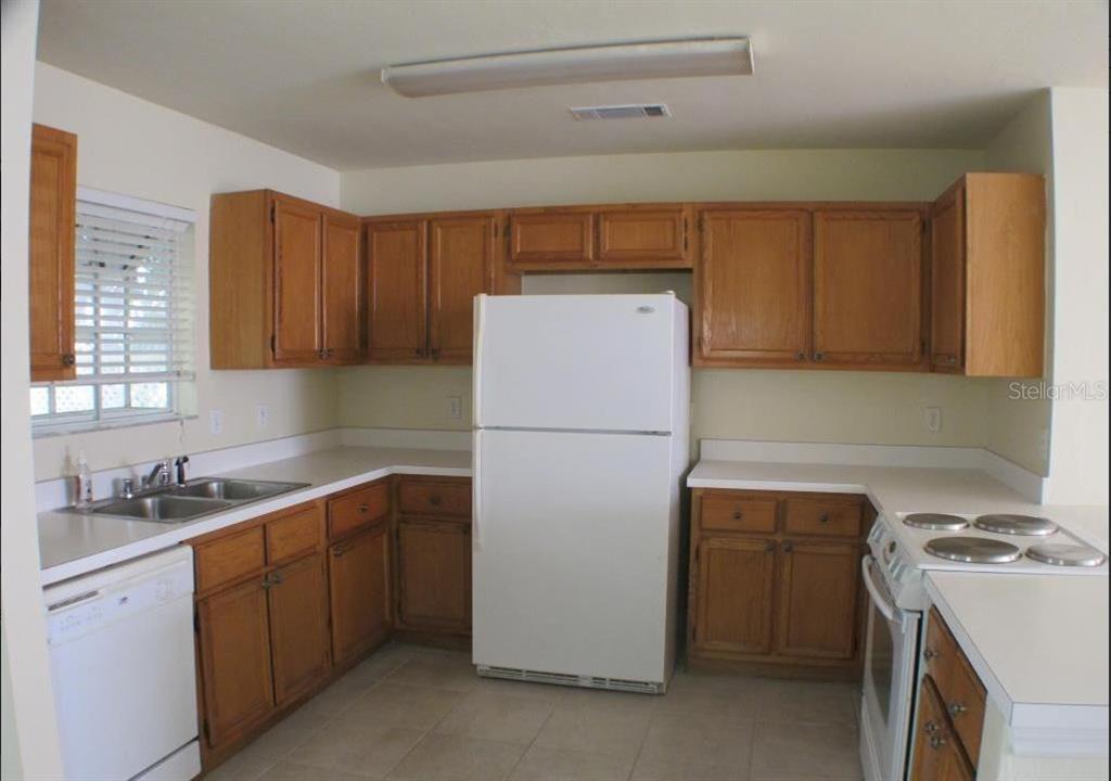 A kitchen with oak cabinets, white appliances, and white countertops in a U-shaped layout — 5205 SW 97TH DRIVE, GAINESVILLE, FL