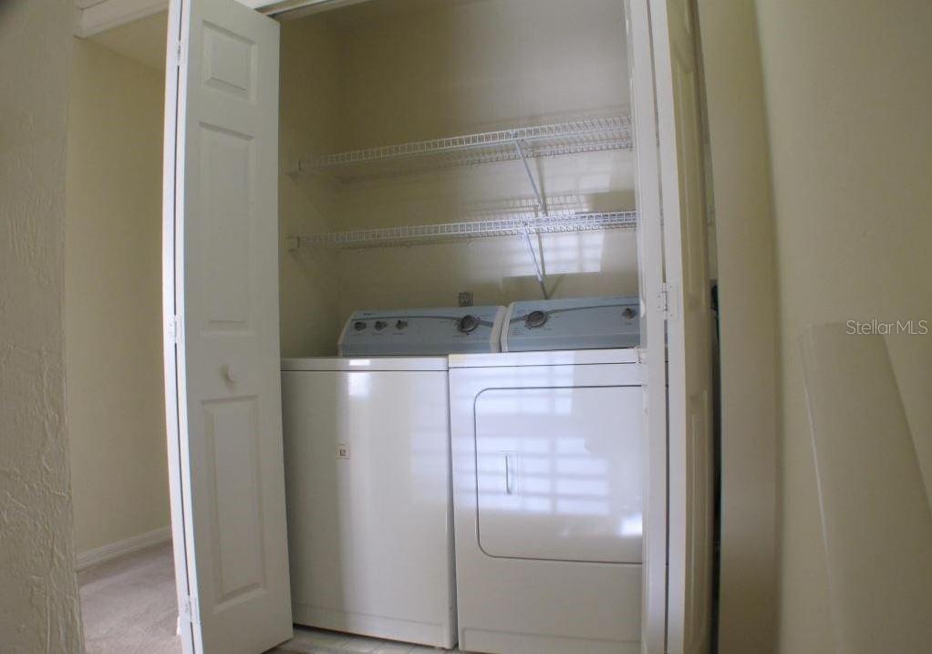 A laundry closet contains a white washer and dryer with wire shelving installed above — 5205 SW 97TH DRIVE, GAINESVILLE, FL