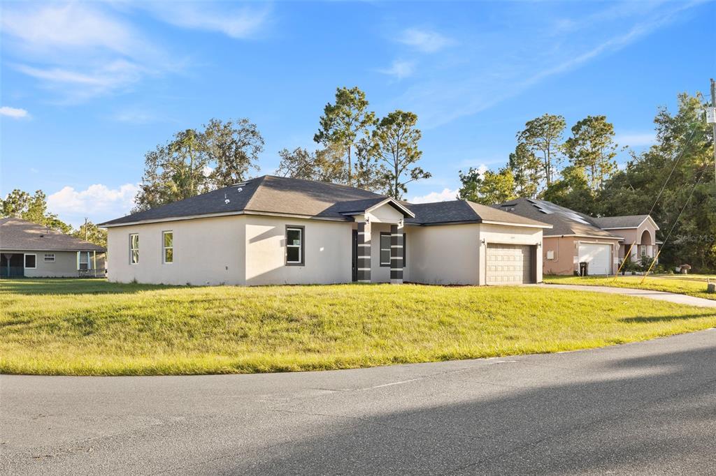 A single-story house with a beige stucco exterior and a two-car garage sits on grass — 6460 SW 129 LOOP, OCALA, FL