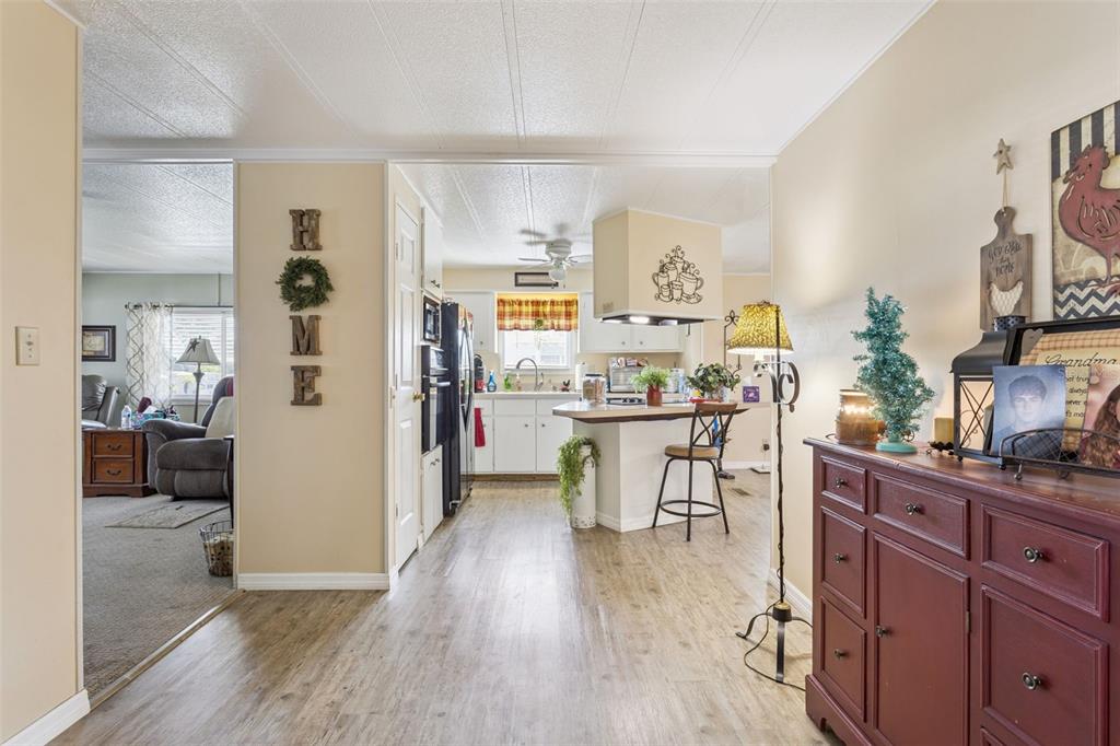 A view from a hallway looking into a kitchen with a breakfast bar and living area — 137 JACARANDA DRIVE, LEESBURG, FL