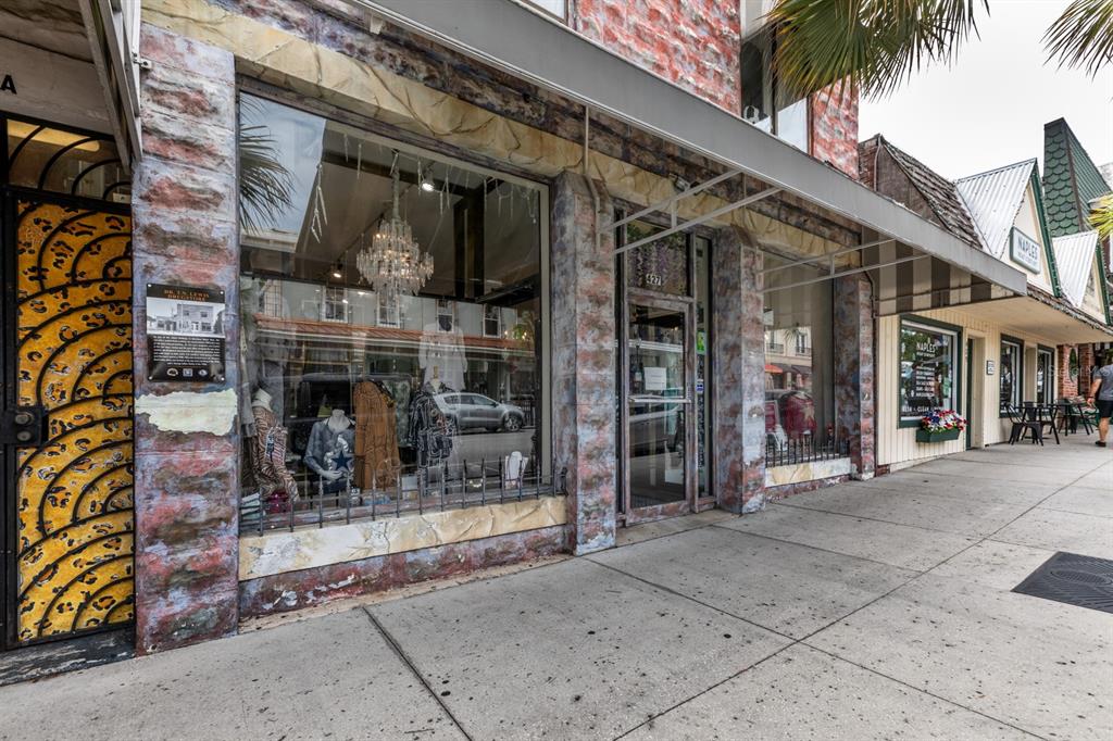 A storefront with a stone facade, large display windows, and a metal awning on a sidewalk — 427 N DONNELLY STREET, MOUNT DORA, FL