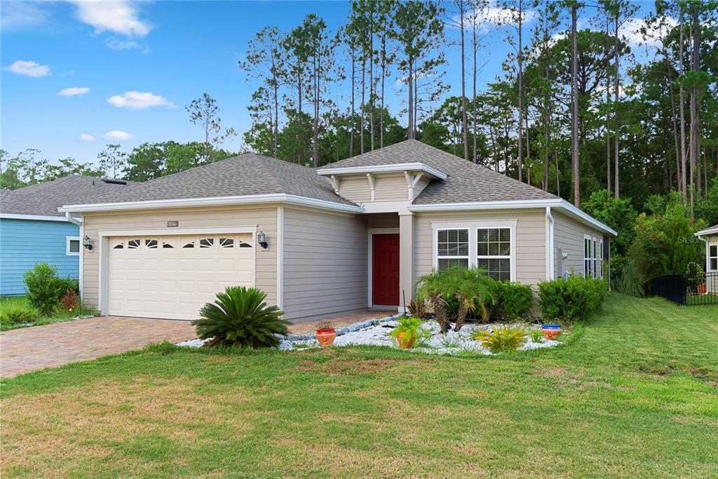 A single-story house with beige siding, a red front door, and a two-car garage — 136 MONTSERRAT DRIVE, ST AUGUSTINE, FL