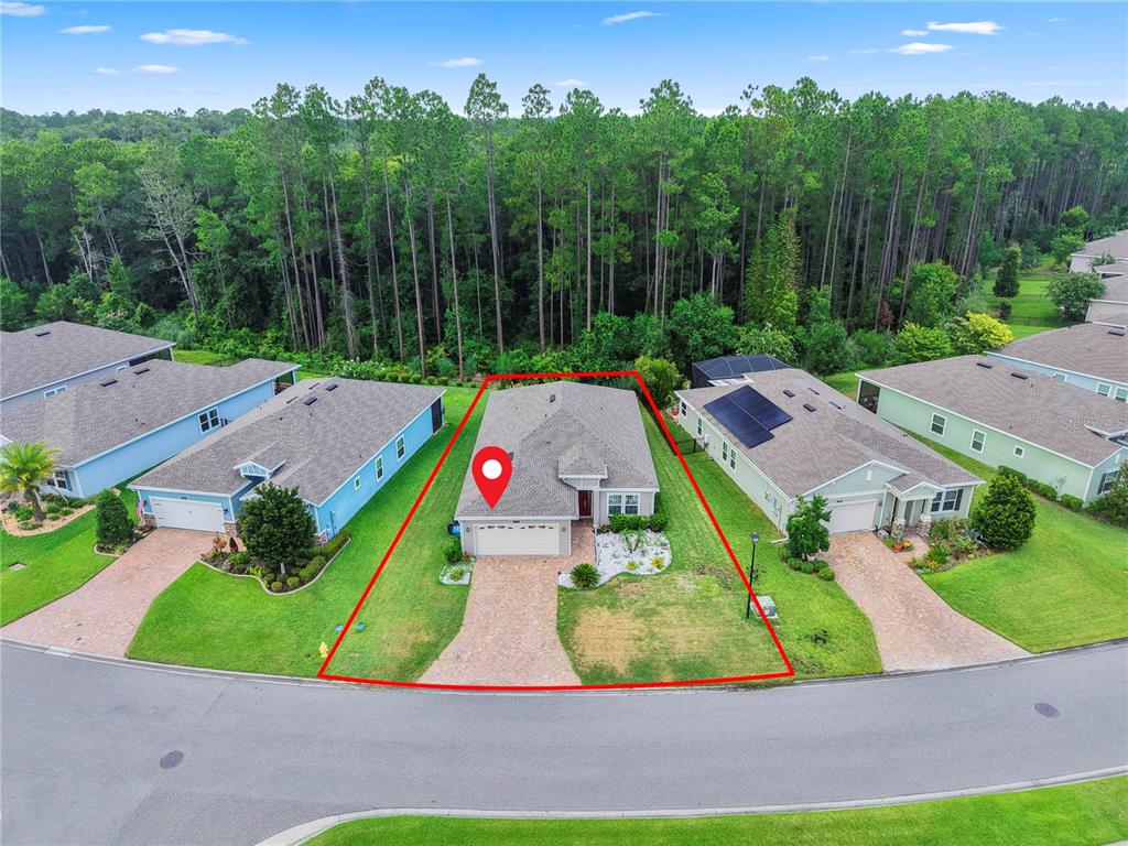 An aerial view shows a single-story house with a paved driveway and a wooded backyard — 136 MONTSERRAT DRIVE, ST AUGUSTINE, FL