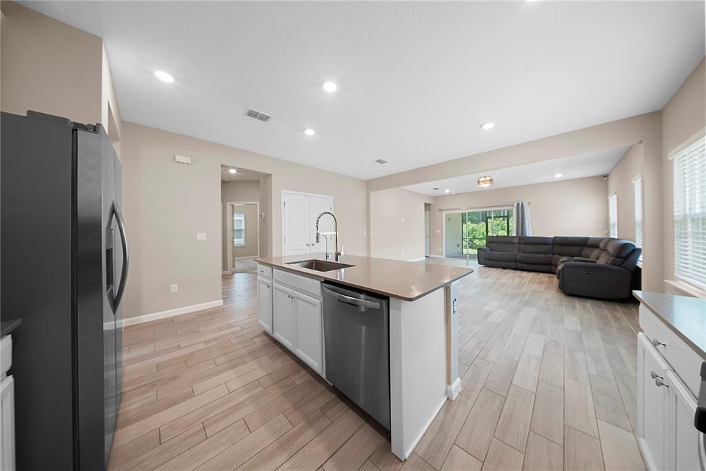A kitchen island with a stainless steel dishwasher faces an open living area with tile floors — 136 MONTSERRAT DRIVE, ST AUGUSTINE, FL