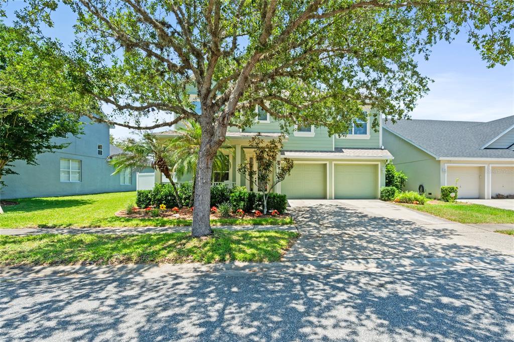A two-story green house with a two-car garage and a front porch under a tree — 4930 ATWOOD DRIVE, ORLANDO, FL