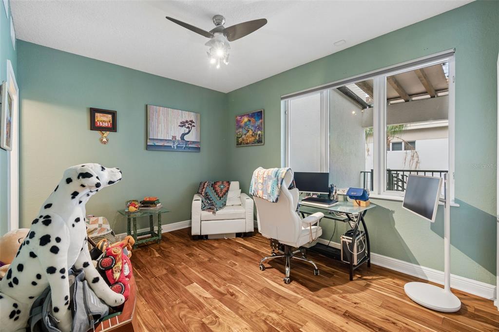 A home office with green walls, wood flooring, a desk, and a large stuffed dalmatian — 1038 BELLASOL WAY UNIT 403, APOLLO BEACH, FL