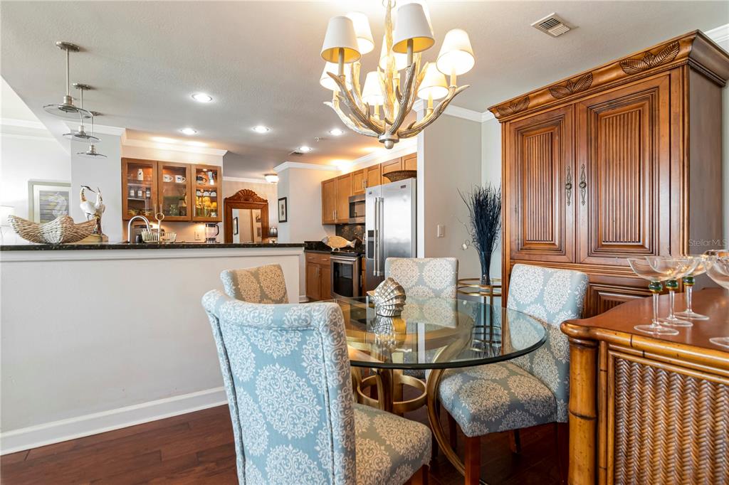 A dining area with a glass table, patterned chairs, and a chandelier near a kitchen — 345 BAYSHORE BOULEVARD UNIT 808, TAMPA, FL