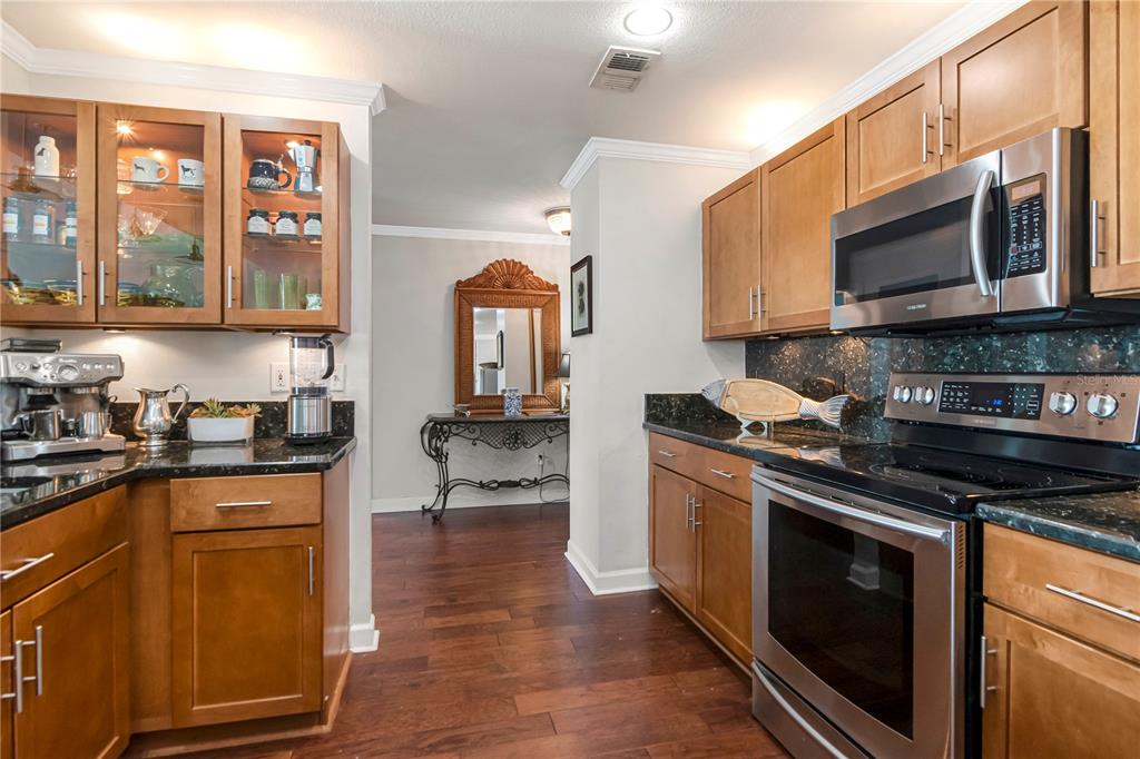 A kitchen features wood cabinets, dark granite countertops, stainless steel appliances, and hardwood flooring — 345 BAYSHORE BOULEVARD UNIT 808, TAMPA, FL