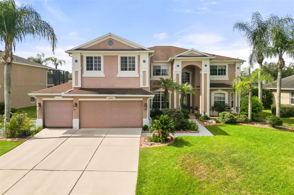 A two-story suburban house with a three-car garage, stucco exterior, and palm trees — 2491 PRAIRIE VIEW DRIVE, WINTER GARDEN, FL