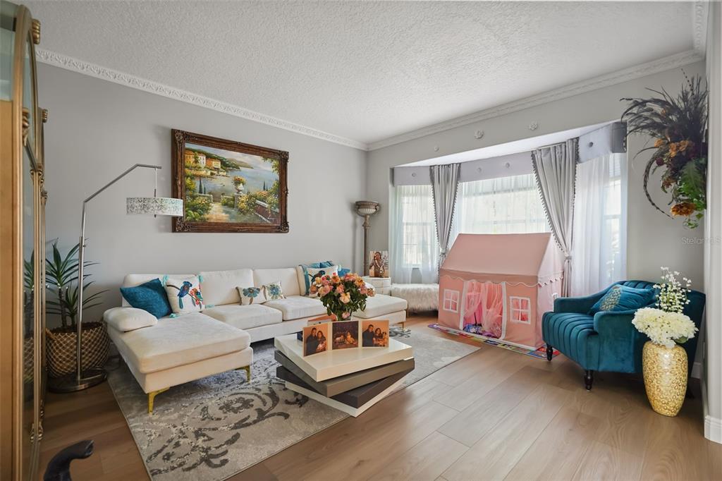 A living room features a white sectional sofa, a tiered coffee table, and a play tent — 2491 PRAIRIE VIEW DRIVE, WINTER GARDEN, FL