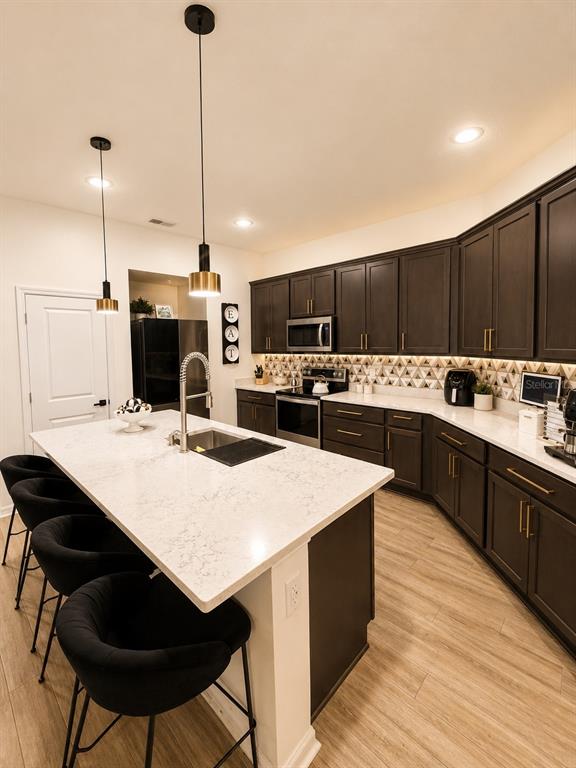 A kitchen features dark cabinets, a white quartz island with bar seating, and pendant lighting — 1743 WILSON PRAIRIE CIRCLE, GROVELAND, FL