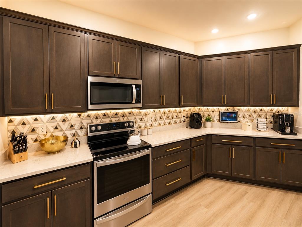 A kitchen features dark wood cabinets, stainless steel appliances, and a geometric patterned tile backsplash — 1743 WILSON PRAIRIE CIRCLE, GROVELAND, FL