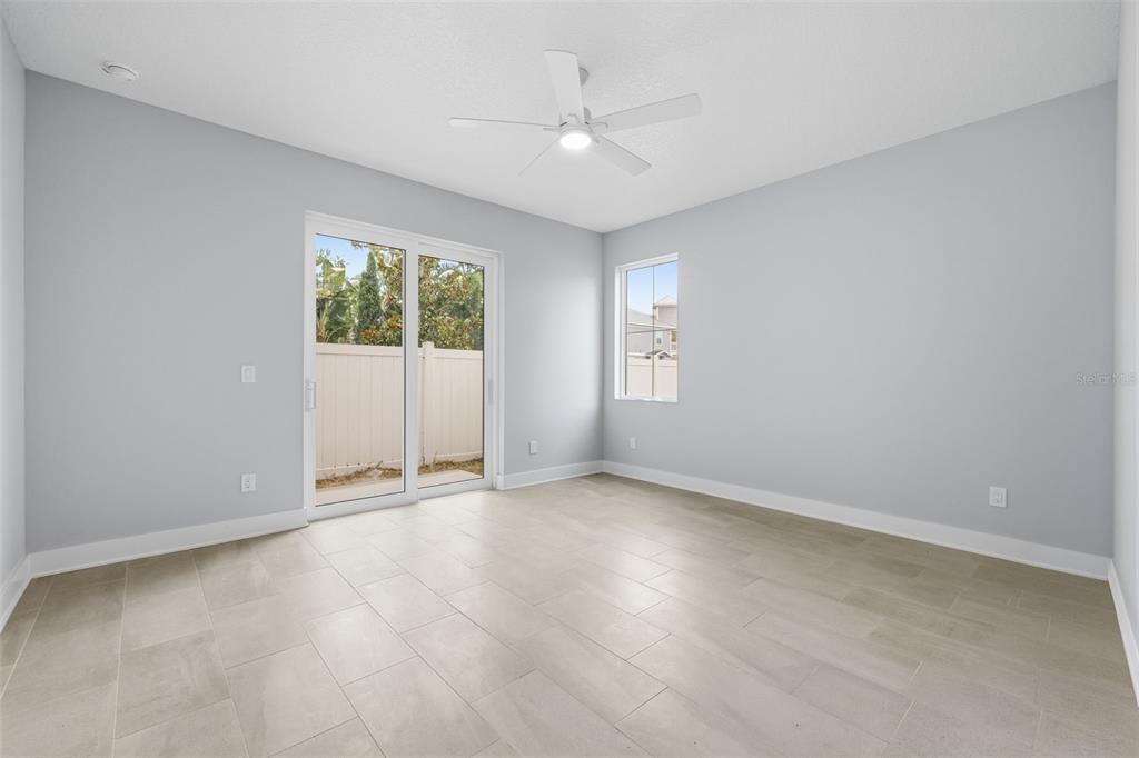 An empty room with light gray walls, tile flooring, a ceiling fan, and sliding glass doors — 4208 W CARMEN STREET UNIT D, TAMPA, FL