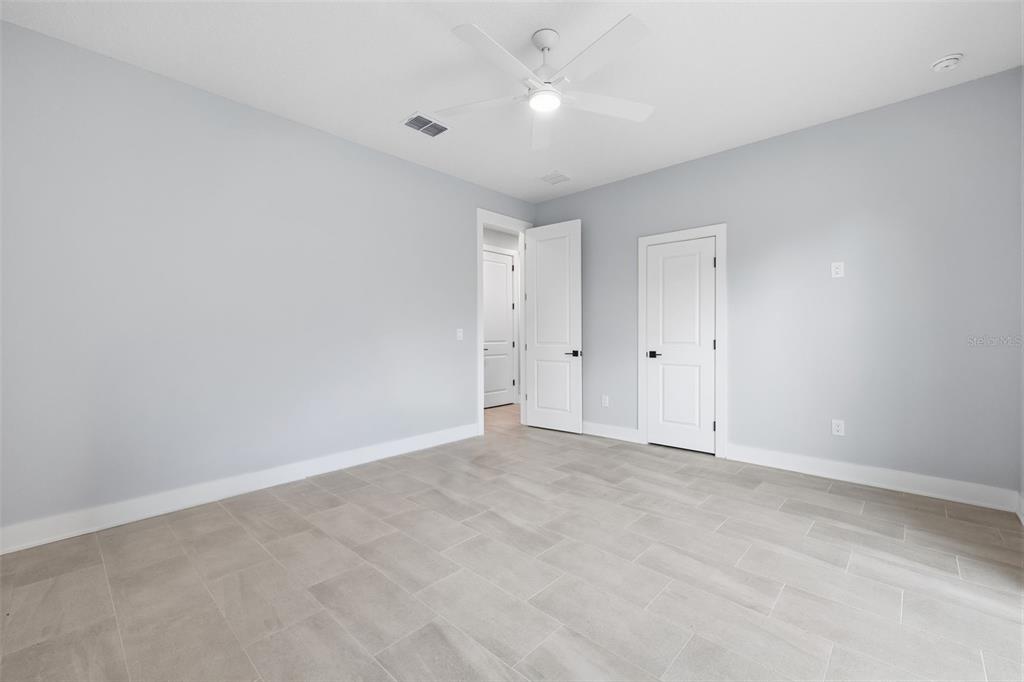 An empty bedroom features light gray walls, white trim, tile flooring, and a ceiling fan — 4208 W CARMEN STREET UNIT D, TAMPA, FL
