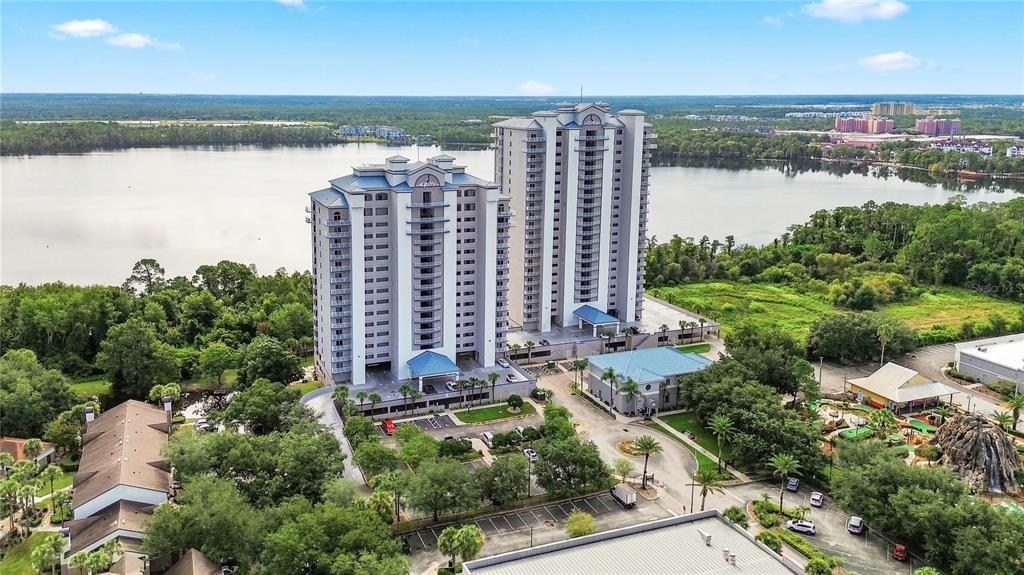 An aerial view shows two tall residential towers situated next to a lake and trees — 13415 BLUE HERON BEACH DRIVE UNIT 1408, ORLANDO, FL