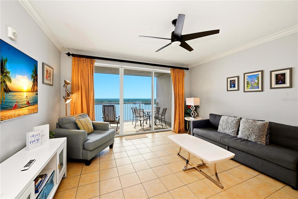 A living room features tile floors, a gray sofa, an armchair, and a balcony view — 13415 BLUE HERON BEACH DRIVE UNIT 1408, ORLANDO, FL