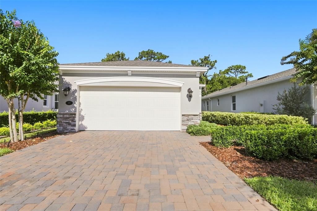The exterior of a single-story house features a two-car garage, stone veneer, and paver driveway — 177 OLD MOSS CIRCLE, DELAND, FL