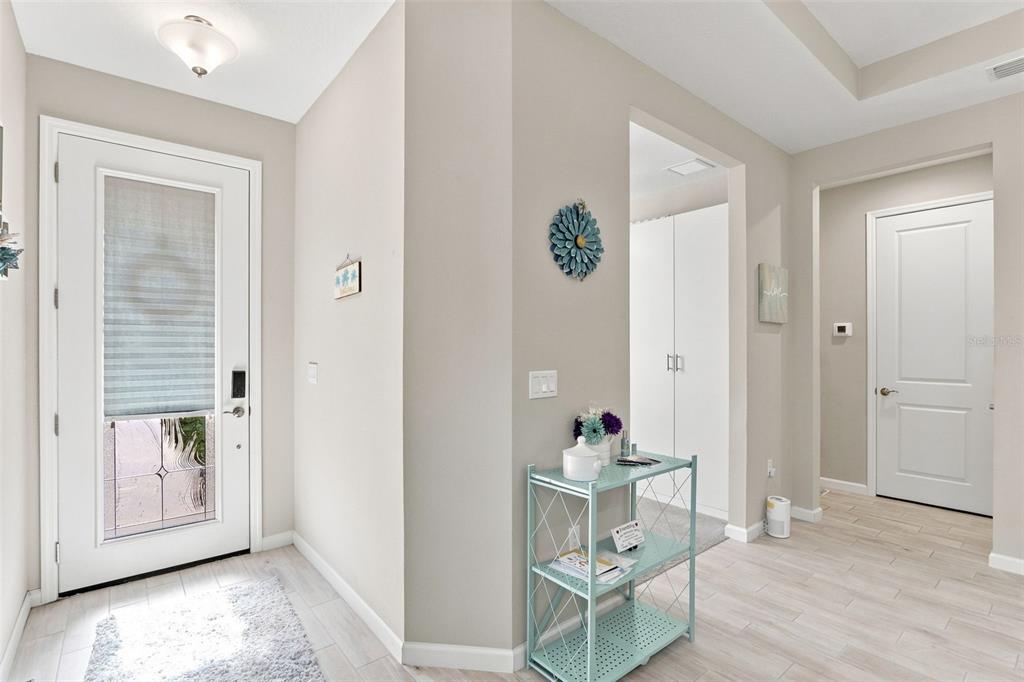 An open-concept living room and kitchen featuring light wood-look tile floors and a gray sectional — 177 OLD MOSS CIRCLE, DELAND, FL