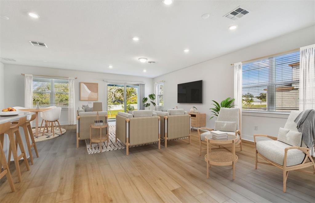 A bright, open-concept living and dining area features light wood flooring and neutral furniture — 9944 JOHNSON OAKS GLEN, PARRISH, FL