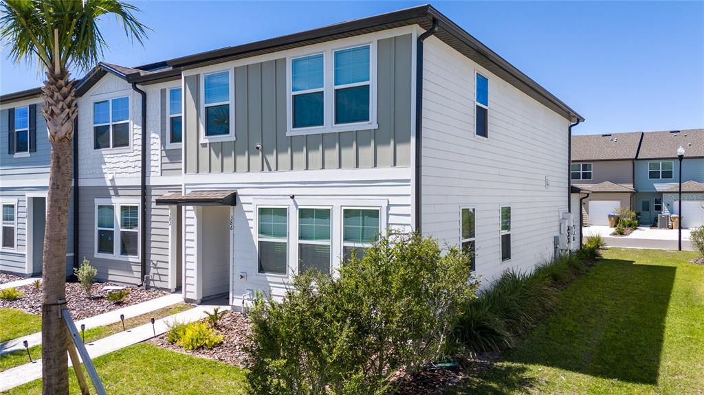 A two-story townhouse exterior with white horizontal siding and a green vertical-paneled section — 386 CADBERRY PLACE, ST CLOUD, FL
