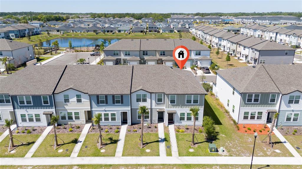 An aerial view shows a row of modern townhomes with gray siding and shingled roofs — 386 CADBERRY PLACE, ST CLOUD, FL