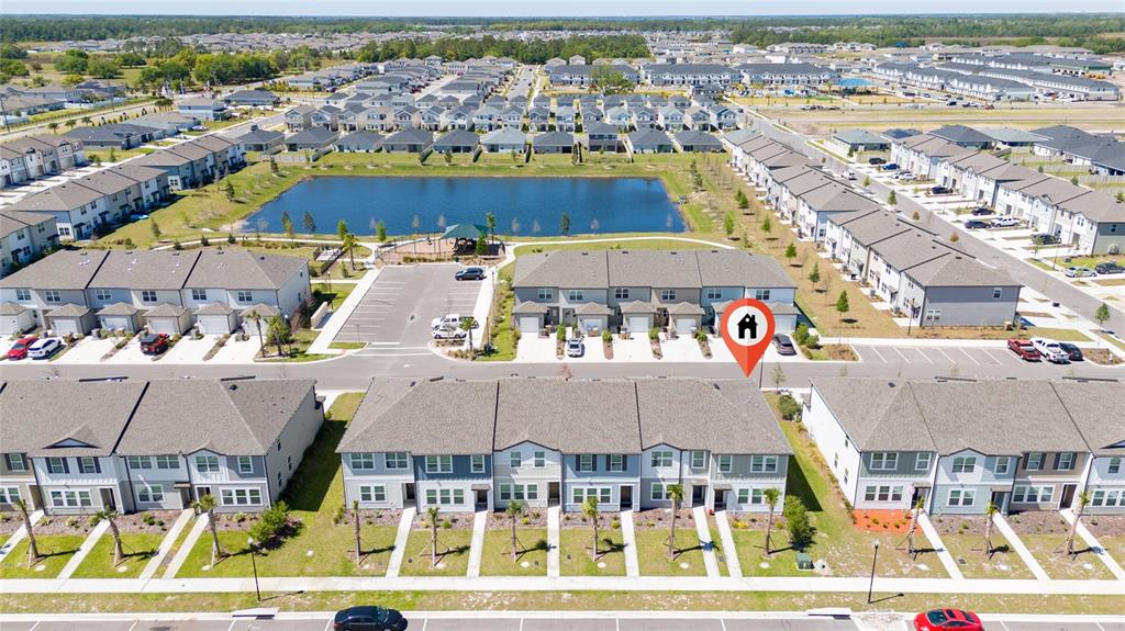 An aerial view shows a residential neighborhood with townhomes, a pond, and parking areas — 386 CADBERRY PLACE, ST CLOUD, FL