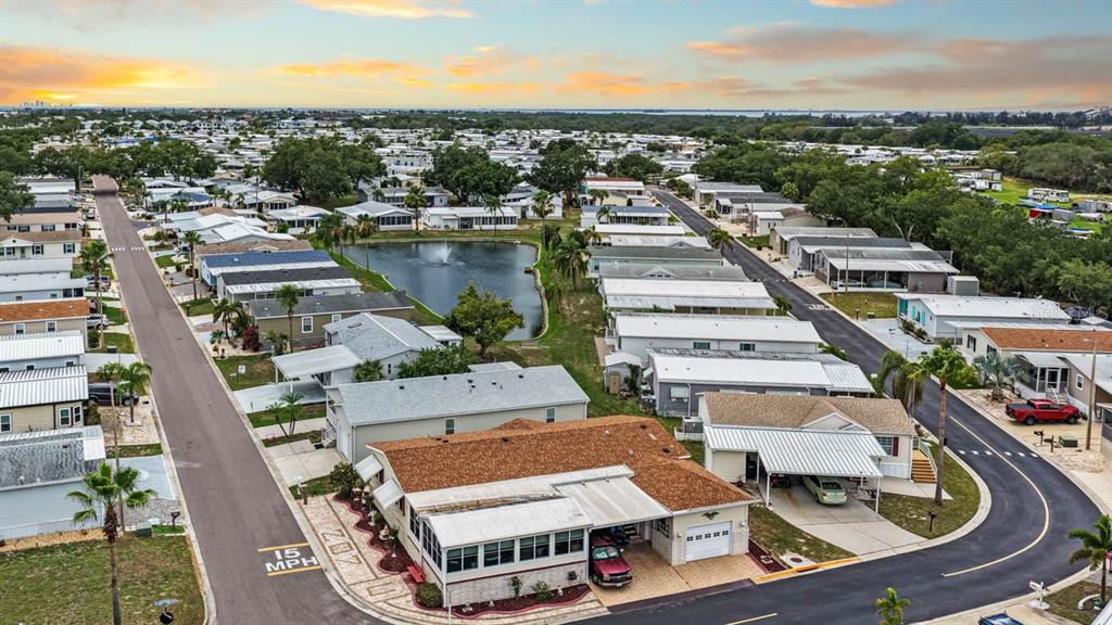 An aerial view shows a residential neighborhood with manufactured homes, a central pond, and streets — 209 S PORT ROYAL LANE, APOLLO BEACH, FL