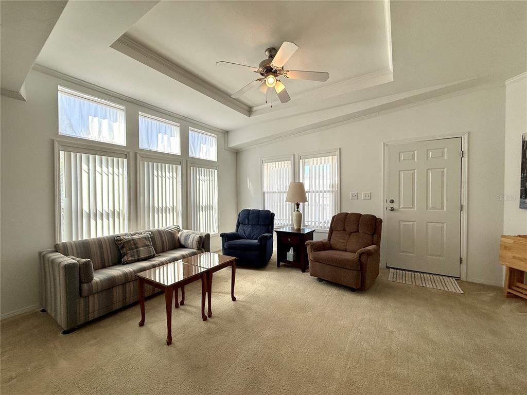 A living room features a striped sofa, two recliners, a coffee table, and large windows — 209 S PORT ROYAL LANE, APOLLO BEACH, FL