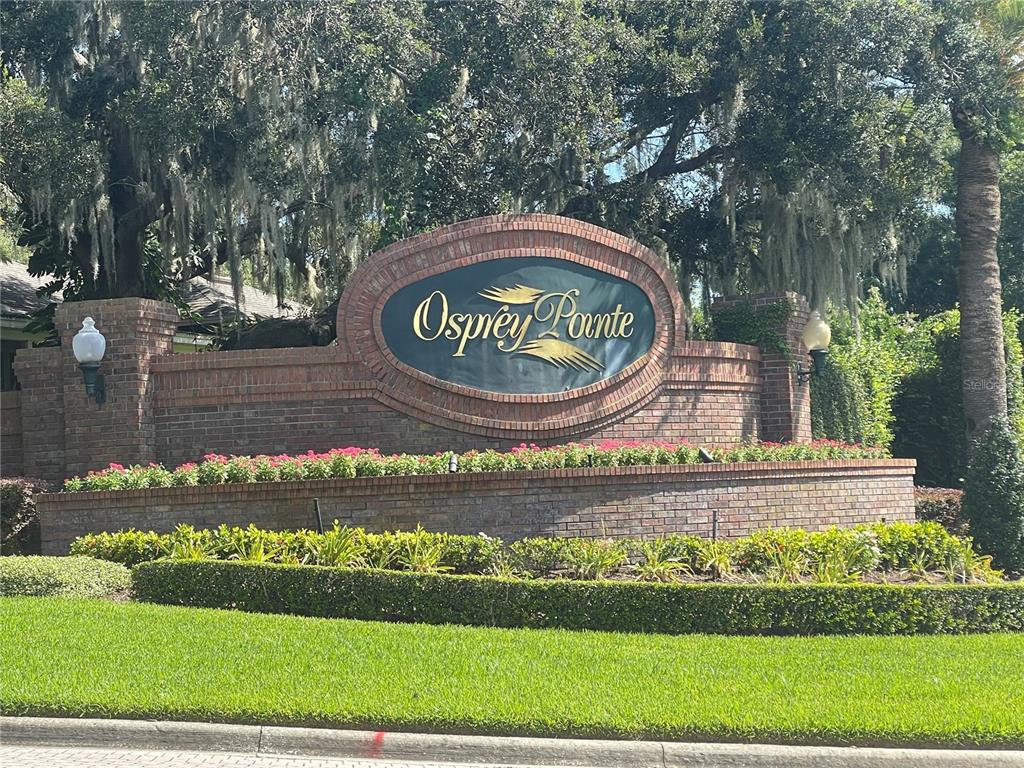 A brick monument sign for Osprey Pointe sits behind a landscaped garden and lawn — OSPREY POINTE BOULEVARD, CLERMONT, FL