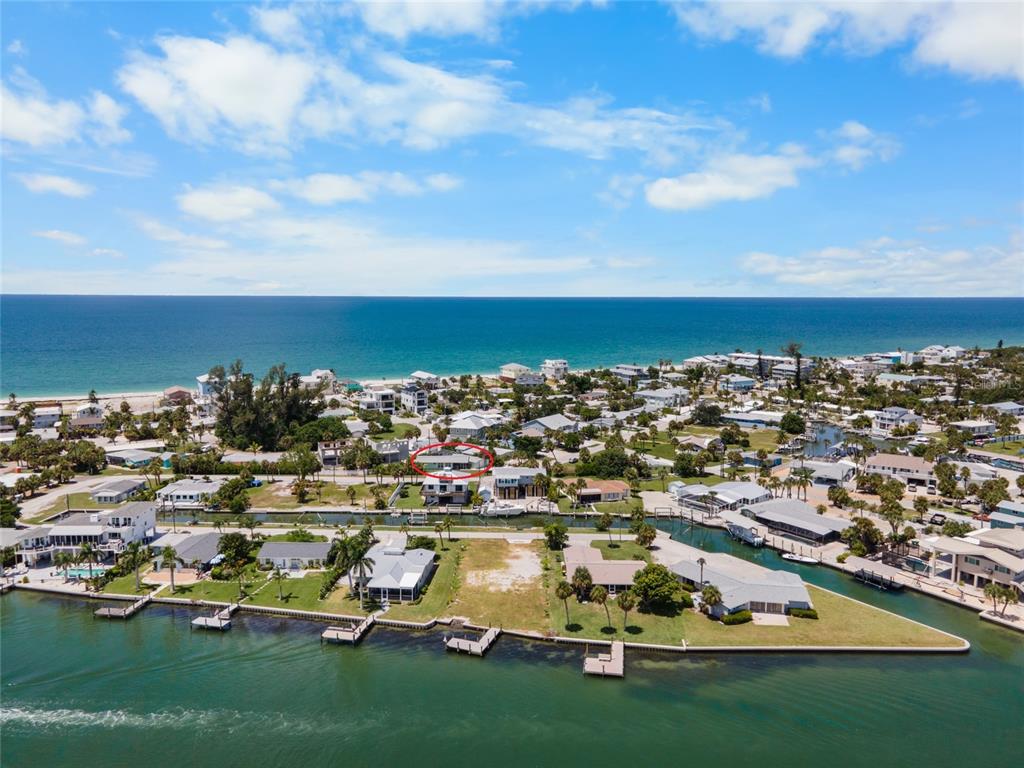 An aerial view shows a coastal neighborhood with a canal, beach, and a marked house — 1280 HOLIDAY DRIVE, ENGLEWOOD, FL