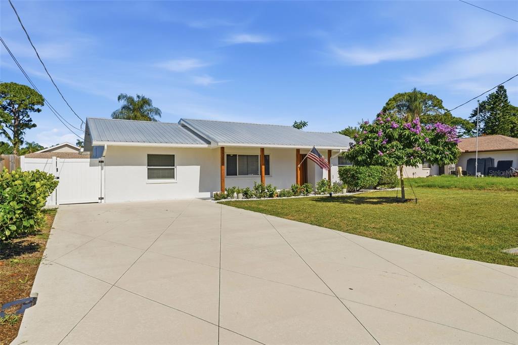 A single-story white house with a metal roof and a flowering tree in the yard — 2600 CAMBRIDGE DRIVE, SARASOTA, FL