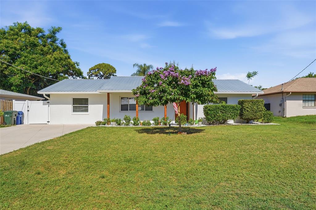 A white single-story house with a metal roof and a front yard with a tree — 2600 CAMBRIDGE DRIVE, SARASOTA, FL