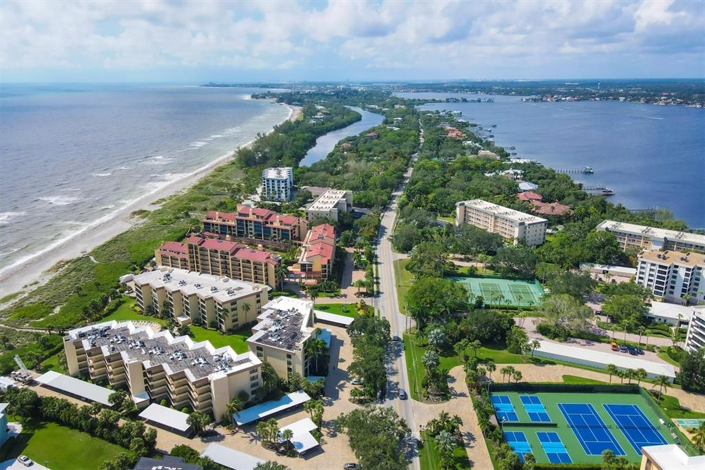 An aerial view of a coastal resort area featuring multi-story buildings, tennis courts, and beaches — 8776 MIDNIGHT PASS ROAD UNIT C107, SARASOTA, FL