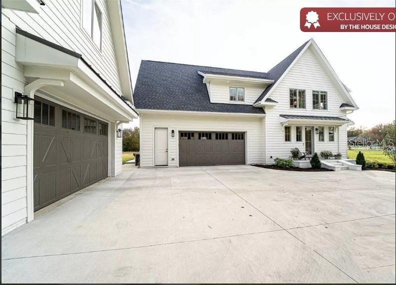 A white house with dark garage doors and a large concrete driveway — 8557 19TH SQUARE SW, VERO BEACH, FL