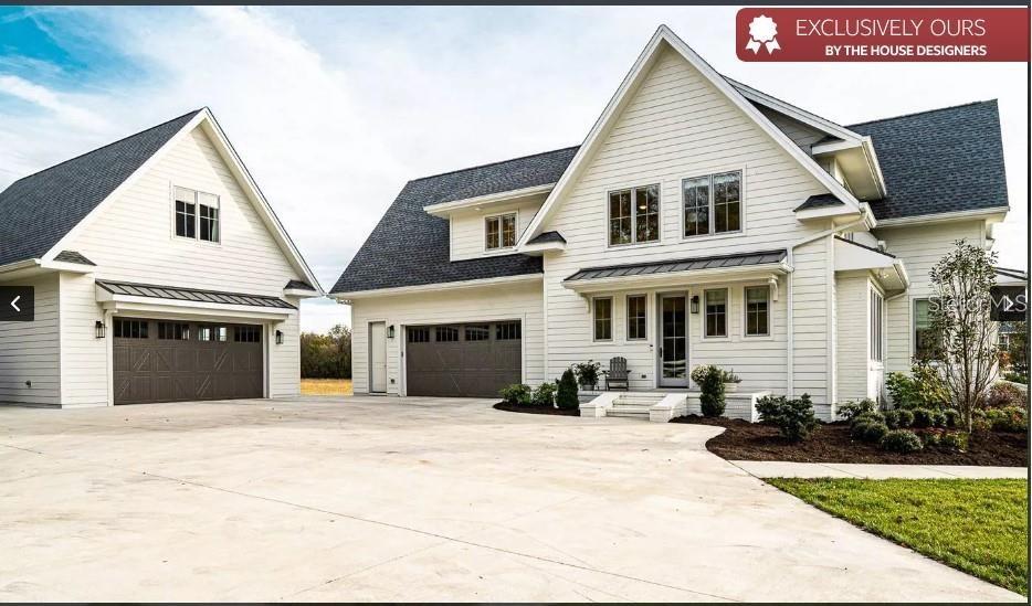 A white farmhouse-style house with a detached garage and a large concrete driveway — 8557 19TH SQUARE SW, VERO BEACH, FL