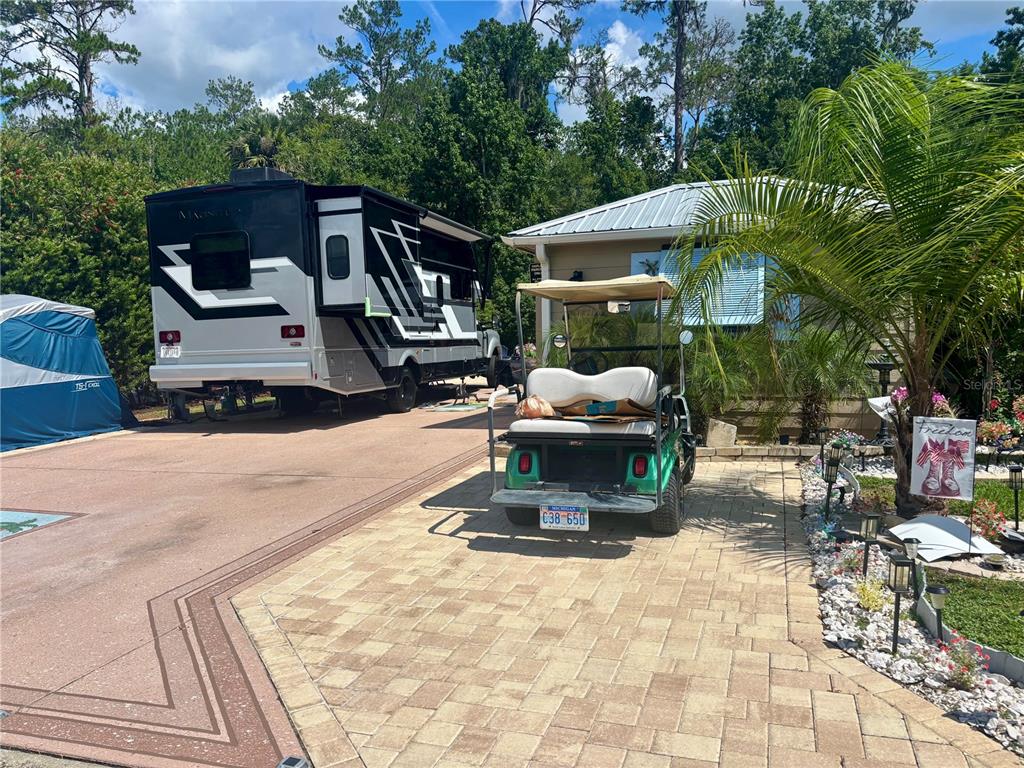 A paved driveway features a large recreational vehicle and a green golf cart parked outside — 10371 NE 28TH LOOP, SILVER SPRINGS, FL