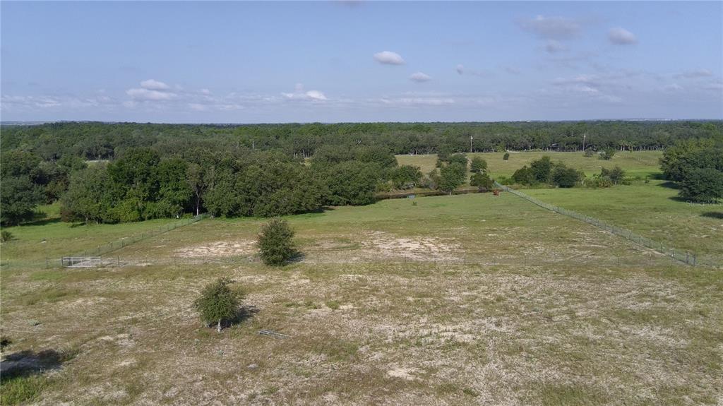 An aerial view shows a large, fenced grassy field bordered by trees and a small pond — 4547 GLEN SAINT MARY ROAD, LAKE WALES, FL