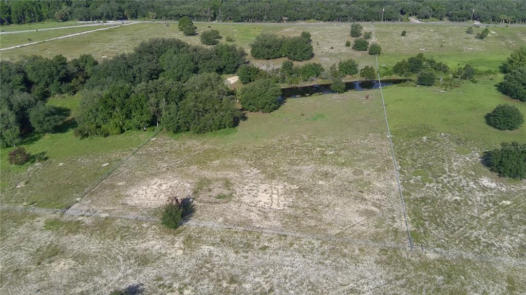An aerial view of a fenced, grassy lot featuring scattered trees and a small pond — 4547 GLEN SAINT MARY ROAD, LAKE WALES, FL