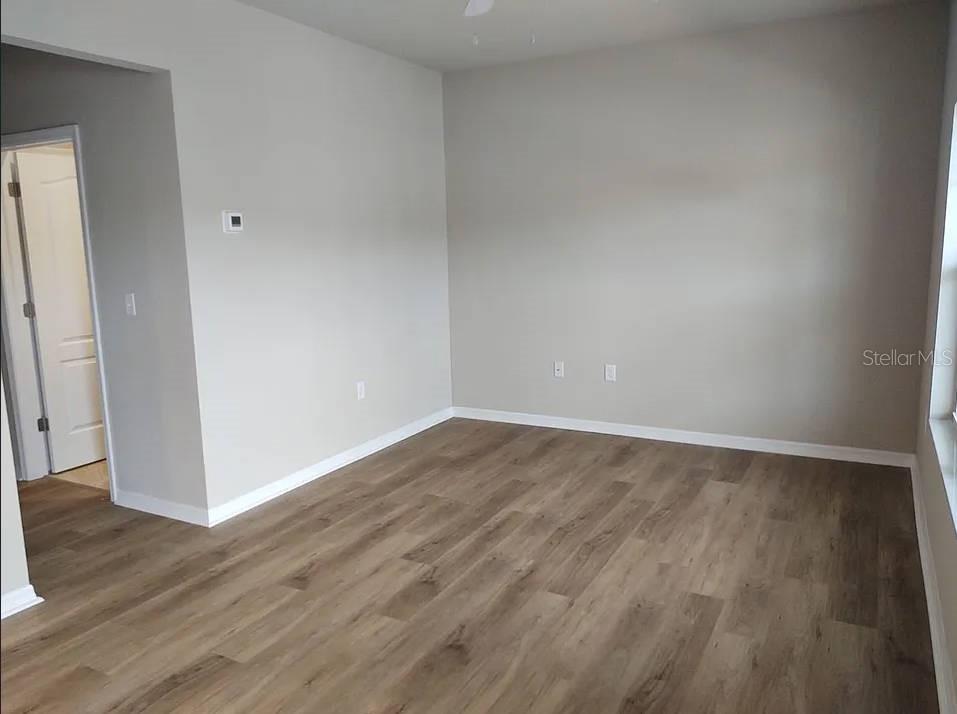 An empty room features light gray walls, white trim, and wood-look vinyl plank flooring — 2609 LANDOVER BOULEVARD UNIT 2617, SPRING HILL, FL