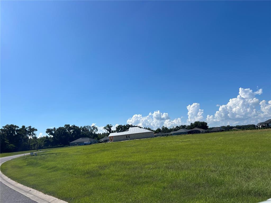 A grassy vacant lot sits next to a house under construction under a blue sky — 000 NW 79TH LOOP, OCALA, FL
