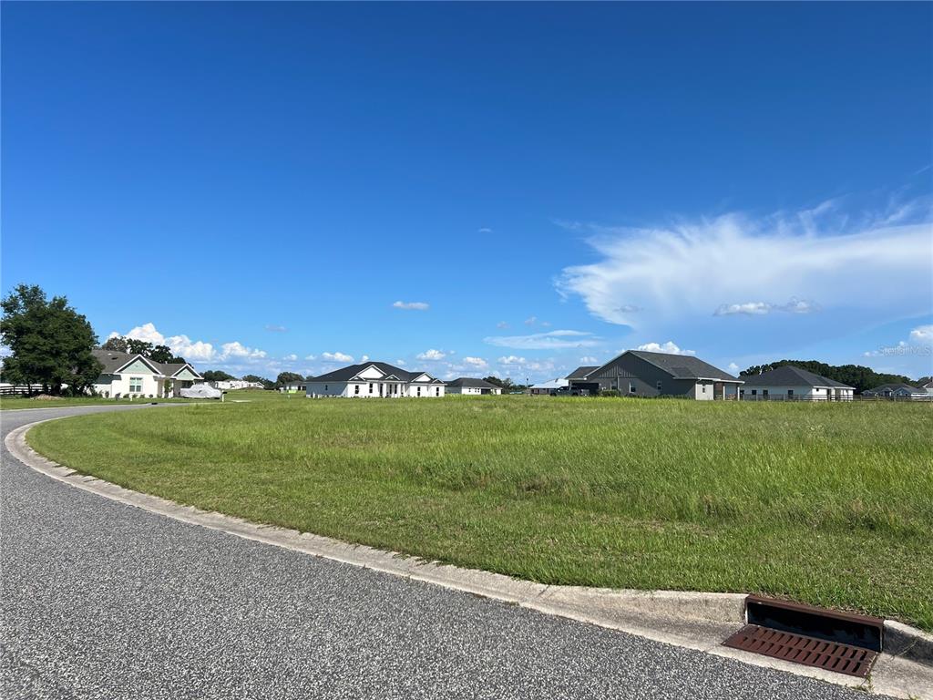 A vacant grassy lot sits in a residential neighborhood with several houses in the background — 000 NW 79TH LOOP, OCALA, FL