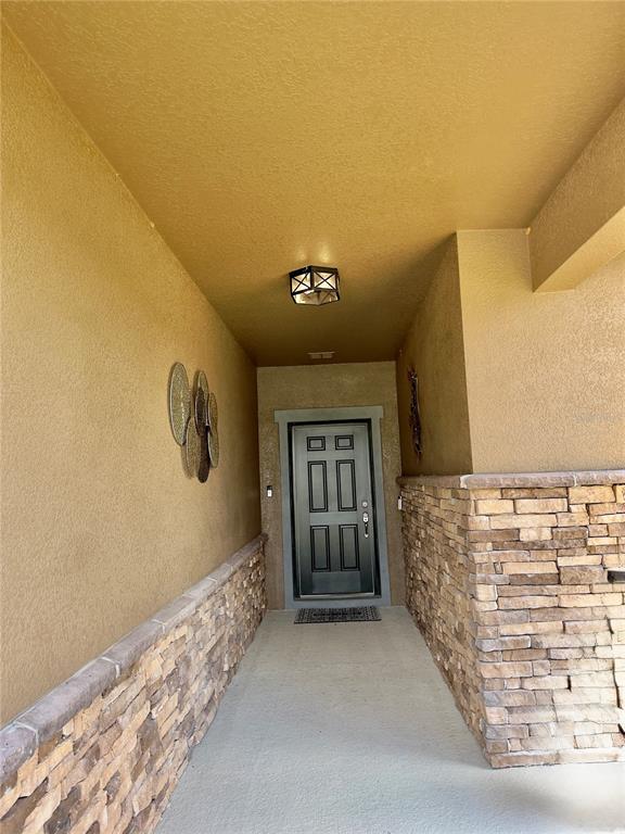 A covered entryway features a dark front door, stone siding, and a ceiling-mounted light fixture — 2098 GOLD DUST DRIVE, MINNEOLA, FL