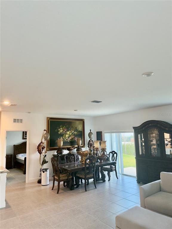 A dining area with a dark wood table and hutch sits near a sliding glass door — 2098 GOLD DUST DRIVE, MINNEOLA, FL